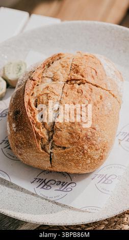 Ein Stück Brot mit einem lila-weißen Etikett darauf. Das Brot wird in zwei Hälften geschnitten und auf eine weiße Platte gelegt Stockfoto