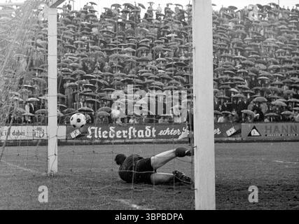 60er Jahre, Sport, Fußball, Regionalliga West, 1966/1967, ETB Schwarz-Weiss Essen vs. SSV Hagen 0-0, 15.05.1967, Stadion am Uhlenkrug in Essen, Spielort, Tor-Chance zur ETB, sparen durch Torwart Helmut Müller (SSV), Spiel bei regnerischem Wetter, Zuschauer mit Schirmen Stockfoto