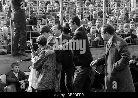 60er Jahre, Sport, Fußball, Regionalliga West, 1967/1968, rot-Weiss Essen vs. Rot-Weiss Oberhausen 1-0, Stadion an der Hafenstraße in Essen, Stewards drängen zwei Jungen mit Vereinsflaggen, die Innenzone des Stadions zu verlassen Stockfoto