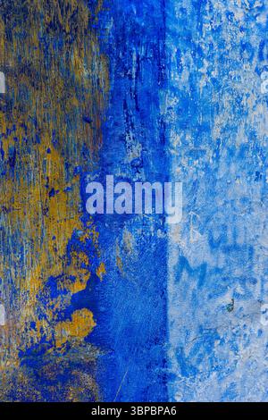 Nahaufnahme einer verwitterten Wand mit abblätternder blauer und gelber Farbe, abstrakter texturierter Hintergrund, Portugal. Stockfoto