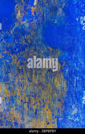 Abstrakte verwitterte Wand mit Schichten lebendiger blauer und gelber Farbe, rustikaler strukturierter Hintergrund, Portugal. Stockfoto