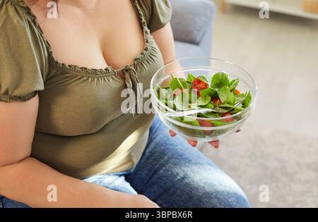 Gesichtslose übergewichtige Frau, die eine Schüssel mit frischem Bio-Gemüsesalat hält Stockfoto