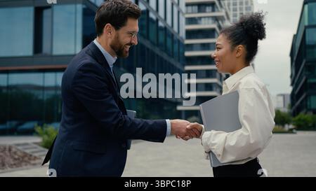 Zwei Geschäftspartner-Kollegen treffen sich in der Stadt Handshake Kaukasischer Geschäftsmann grüßt Handschütteln afroamerikanische Geschäftsfrau Kollegen gehen Stockfoto