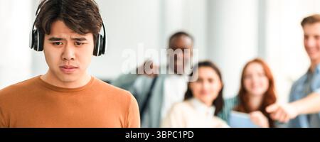 Die Leute spotten und machen sich über traurigen asiatischen Mann lustig Stockfoto