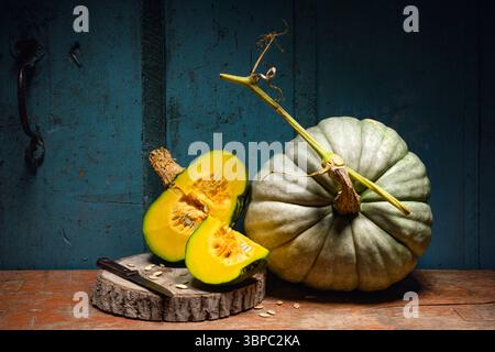 Kürbisse auf einem alten Holztisch mit Messer und Samen im rustikalen Stil. Thanksgiving oder Halloween Hintergrund. Herbstkürbis-Konzept Stockfoto