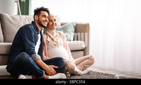 Glückliche islamische Ehegatten erwarten EIN Baby, das zusammen zu Hause ruht Stockfoto