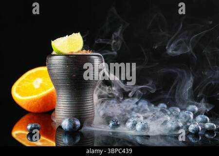 Shisha Schüssel mit Rauch und Früchten auf schwarzem Tisch, Nahaufnahme Stockfoto