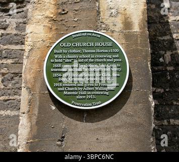 Historische Gedenktafel auf einer Steinmauer, die die Geschichte des Old Church House in Bradford auf Avon zeigt und seine verschiedenen Nutzungsmöglichkeiten über Jahrhunderte hervorhebt Stockfoto