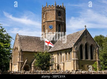 Eine historische englische Kirche von St. Mary's in Uffington Oxfordshire mit einem Steinturm und der Flagge von St. George unter blauem Himmel Stockfoto