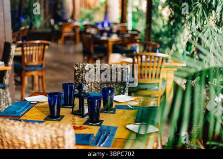 Tische mit blauem Glasgeschirr und lebhafte Tischdekorationen laden zum Essen in lebhafter Atmosphäre ein. Stockfoto