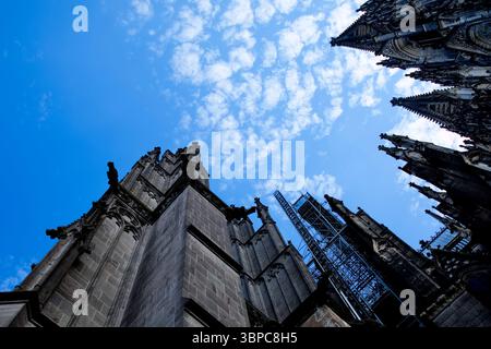 Gotische Türme des Kölner Doms erheben sich kraftvoll in einen lebendigen Himmel, von unten mit dramatischen Winkeln und Steindetails, die die Geschichte widerspiegeln Stockfoto