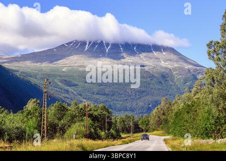 Die Straße Gaustavegen nach Rjukan (Telemark, Norwegen) mit dem Berg Gaustatoppen (1883 m Höhe) bedeckt von Wolken. Stockfoto