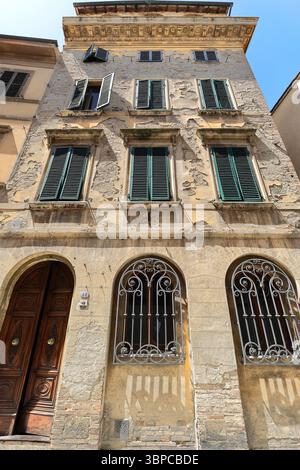 Fünfstöckiges Gebäude im Stil der Spätrenaissance aus dem Jahr 042 an der Via di Voltaia nel Corso, abgesplitterte Fassade mit darunter liegenden Ziegelsteinen. Montepulciano-Toskana-Italien. Stockfoto