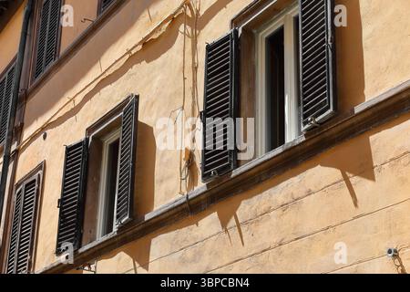 047 pfirsichfarbene Fassade eines Hauses an der Westseite der Via dell'Opio nel Corso mit Fenstern aus braun lackiertem Holz. Montepulciano-Toskana-Italien Stockfoto