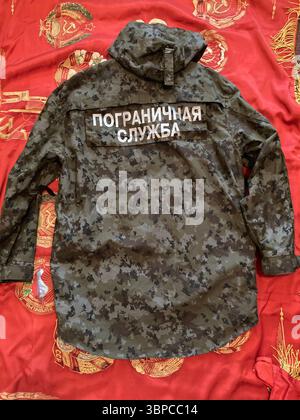 Tarnjacke der russischen Grenzwache mit kyrillischem Patch auf sowjetischem Banner Hintergrund Stockfoto