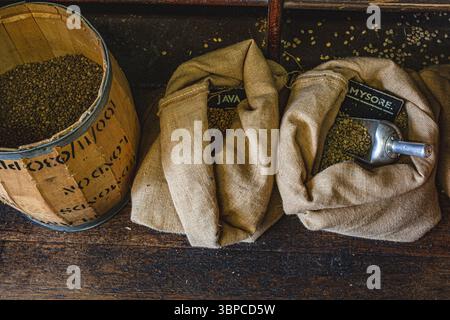 Kaffeesäcke gefüllt mit frischen Kaffeebohnen und Metall-Schaufel-Coffee Specialist Shop. Stockfoto