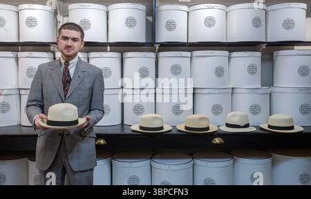 Männlicher Ladenassistent hält Classic Panama bei Lock & Co. Hatters in London. Stockfoto
