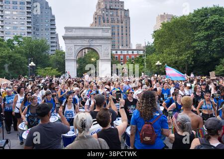 Eine große Menschenmenge, viele mit Instrumenten, versammelt sich in einem Park in der Nähe eines Triumphbogens. Die Teilnehmer tragen verschiedene Kleidung und einige halten Schilder. Stockfoto