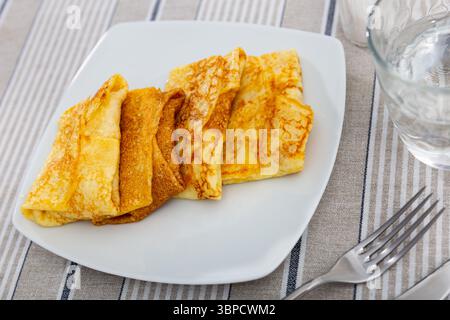 Pfannkuchen gefüllt mit süßer Beerenschokolade werden mit einer Tasse heißem grünem Tee serviert Stockfoto