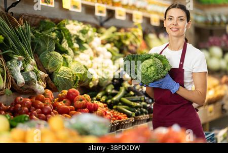 Weibliche Lebensmittelläden bieten Reifen Brokkoli-Kohl in der Lebensmittelabteilung des Supermarktes an Stockfoto