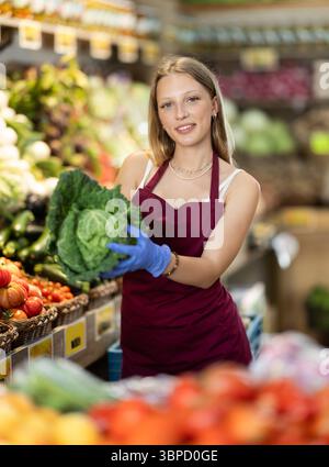Weibliche Lebensmittelläden bieten Reifen Brokkoli-Kohl in der Lebensmittelabteilung des Supermarktes an Stockfoto