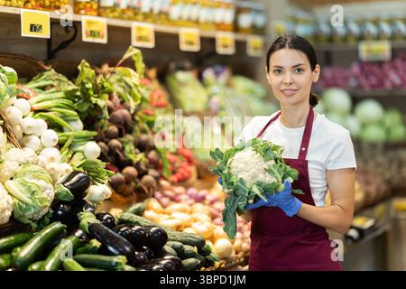Weibliche Lebensmittelläden bieten Reifen Brokkoli-Kohl in der Lebensmittelabteilung des Supermarktes an Stockfoto