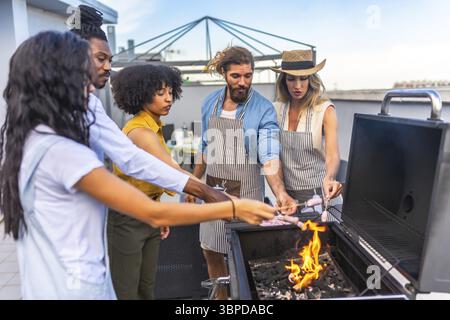Köche grillen Würstchen auf einem Dach, genießen eine lebhafte Party mit Freunden und bereiten köstliche Mahlzeiten unter dem sonnigen Himmel zu Stockfoto