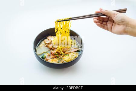 Gelbe Nudeln von Hand aus einer Schweinennudelschüssel auf weißem Hintergrund für Werbung Stockfoto