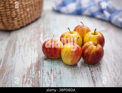 Frisch gepflückte Äpfel von einem Bauernhof, auf einem verwitterten Holztisch angeordnet. Halten Sie die natürliche Schönheit und Textur der Äpfel und des Tisches fest, betonte Zinnen Stockfoto