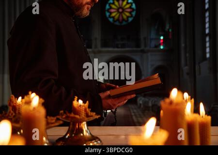 Kaukasischer Mann mittleren Alters, der Buch während der religiösen Zeremonie in der Kirche liest Stockfoto