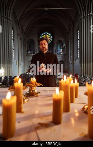 Kaukasischer Mann beleuchtet Kerzen während der religiösen Zeremonie in der Kirche Stockfoto