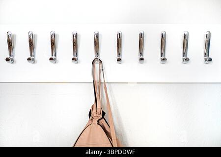 Lederrucksack hängt an einem Kleiderbügel mit Metallhaken in einem Klassenzimmer, Büro. Zurück zur Schule Stockfoto
