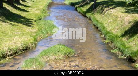 Im historischen Koprivshtitsa, Bulgarien, fließt der klare Fluss durch üppige grüne Ufer unter der Sommersonne. Schaffen Sie eine friedliche und ruhige Naturszene Stockfoto