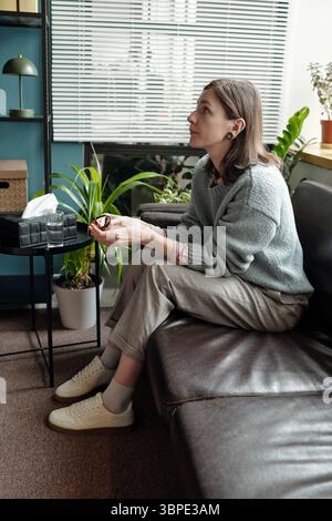 Junge Frau, die auf dem Sofa sitzt und an der Therapiesitzung teilnimmt Stockfoto