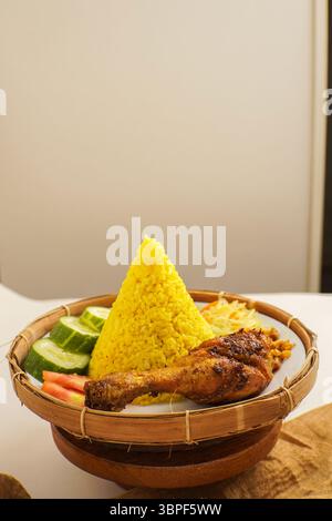 Blick von oben auf traditionellen indonesischen gelben Reis mit Sambal, Tempeh, Nudeln und Gemüse serviert auf einem Teller. Stockfoto