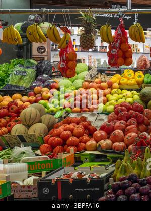 Eine farbenfrohe Ausstellung frischer Produkte, darunter Tomaten, Melonen und Bananen, in einem Obst- und Gemüsestand auf dem Markt La Boqueria, Barcelona, Spanien. Stockfoto