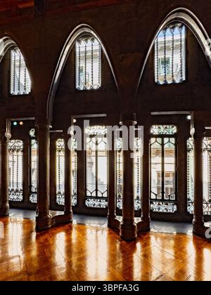 Das große Wohnzimmer des Palau Güell von Antoni Gaudí, mit polierten Marmorsäulen und großen Fenstern, die dramatisches Licht erzeugen, Barcelona, Spanien. Stockfoto