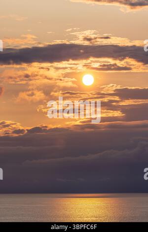 Atemberaubender Sonnenuntergang über dem Meer in der Nähe von Dänemark, von einem Kreuzfahrtschiff erfasst. Windturbinen bilden den Horizont unter leuchtendem Rot- und Orangenhimmel. Stockfoto