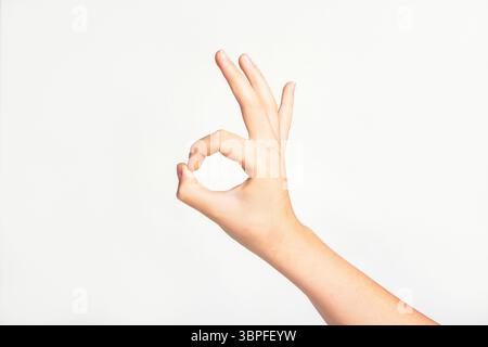 Frauenhand, die gut gestickt oder OK auf hellgrauem Hintergrund. Stockfoto