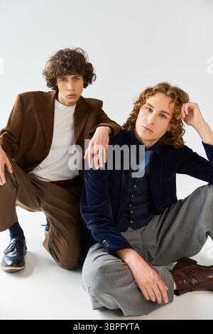 Zwei modische Freunde posieren selbstbewusst in eleganter Kleidung mit verspieltem Ausdruck und versprühendem Charme. Stockfoto