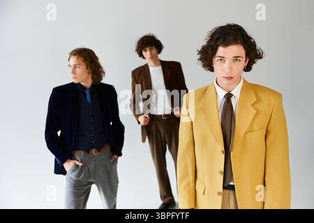 Drei junge Männer zeigen ihren Stil in trendigen Outfits und teilen einen fröhlichen Moment miteinander. Stockfoto