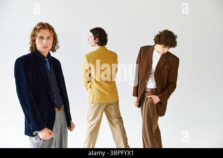 Drei Männer drücken ihre individuellen Stile selbstbewusst aus, während sie in einem hellen Studio posieren. Stockfoto