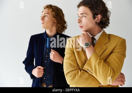Zwei Männer in modischen Outfits posieren selbstbewusst zusammen und präsentieren ihre einzigartigen Styles. Stockfoto