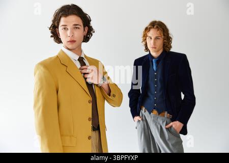 Zwei junge Männer posieren selbstbewusst und bringen ihren einzigartigen Modesinn in einer lebhaften Atmosphäre zum Ausdruck. Stockfoto