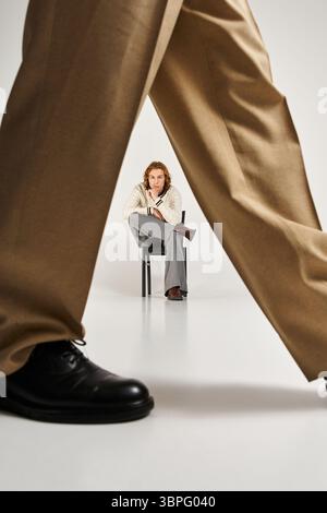 Zwei stilvolle junge Männer posieren selbstbewusst und präsentieren ihre einzigartigen Looks in einer minimalistischen Umgebung. Stockfoto