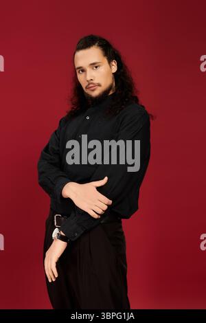 Ein junger Mann mit einem gepflegten Bart zeigt sein Charisma, während er ein schwarzes Hemd trägt. Stockfoto