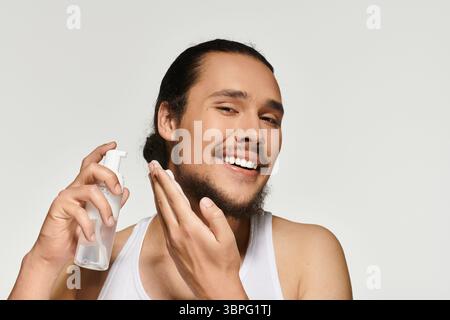 Ein hübscher junger bärtiger Mann wendet gerne Hautpflege an und zeigt ein fröhliches Verhalten. Stockfoto