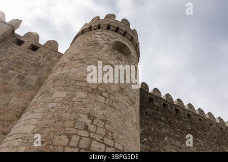 Alte Steinfestung mit rundem Turm unter bewölktem Himmel, beispielhaft für historische Architektur und mittelalterliche Verteidigungsentwürfe. Baku Festung, Azerb Stockfoto