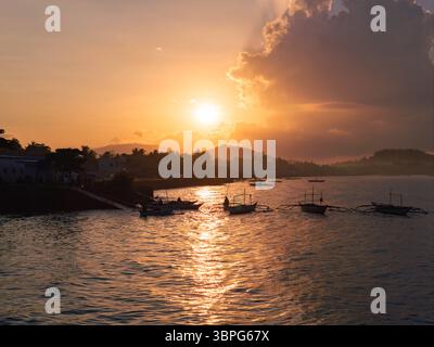 Aus der Vogelperspektive des strahlenden Sonnenlichts, das die Wasseroberfläche küsst und die Boote in der Nähe des Banate Fish Port, Banate, Western Visayas, Philippinen beleuchtet. Stockfoto
