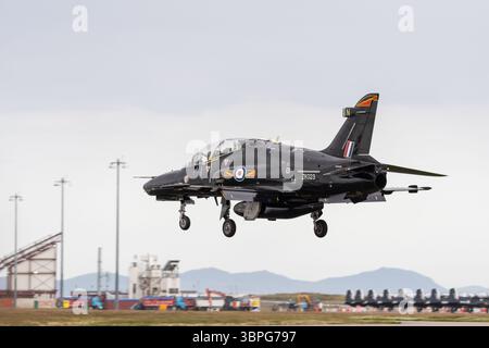 ZK023: Die Royal Air Force BAE Hawk T2 kommt im RAF Valley, Anglesey, Wales an, wobei Beechcraft Texan T1s im Hintergrund geparkt sind Stockfoto